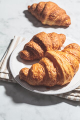 Fresh croissants on white marble background.