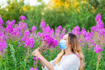 Girl in a medical mask sniffs a bouquet of flowers while walking in the park