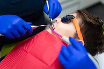 Dentist and assistant make preventive dental plaque cleaning for teenager