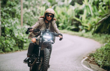 Schönes Mädchen, das Spaß daran hat, ihr benutzerdefiniertes Cafe Racer-Motorrad zu fahren