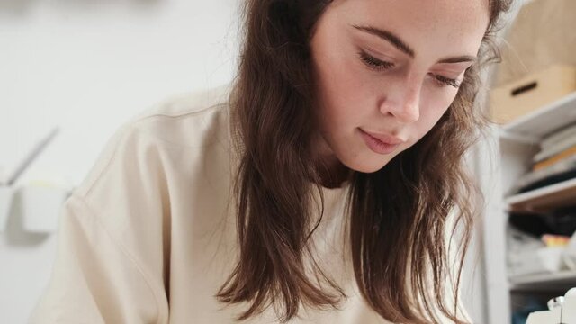 A close-up view of a focused young woman seamstress is working at the design studio