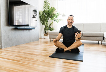 Man on a mat doing some exercise at home using cellphone to help training