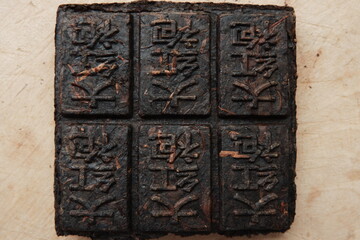 Pressed tea with hieroglyphs. Black Tiled Puerh Tea. Translation: 