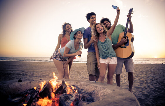 Group Of Friends Having Fun On The Beach Making A Bonefire. People Spending Time Together In California, Los Angeles