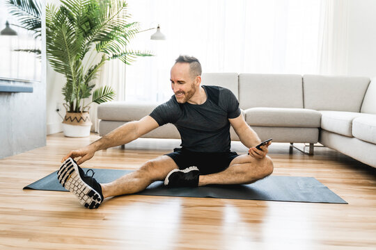 Man on a mat doing some exercise at home using cellphone to help training