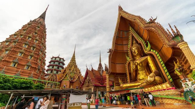 Tourists take a walk and take pictures of Golden Chedi on a hill at Wat Tham Sua, Kanchanaburi Landmark Thailand, Time lapse