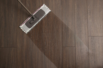 Cleaning of wooden floor with mop, top view. Space for text