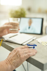 Fototapeta premium Senior citizen measuring vitals and consulting doctor online from home