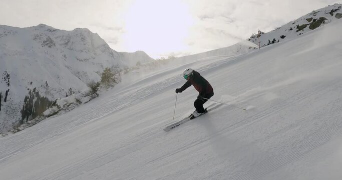 Professional male skier skiing fast ski turns on perfect ski slope in tyrol. Beautiful landscape in the mountains with sporty ski turns in the mountains. Skiing, Snow, Mountains, Alps, Ski shooting.