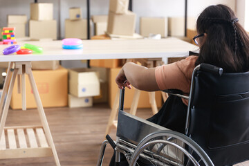 A lonely child Asian autistic girl sits in a wheelchair and looks out the window to feel lonely at home during the COVID-19 epidemic.