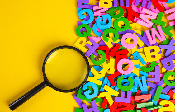 Magnifying glass with colorful alphabet on yellow background, Copy space.Education concept.