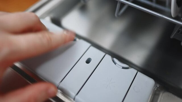 Man putting detergent tMan putting detergent tablet into dishwasher.ablet into dishwasher.
