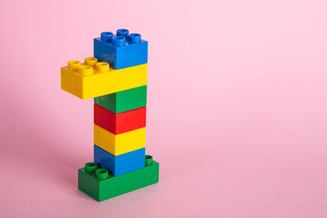 Color plastic building blocks on pink background