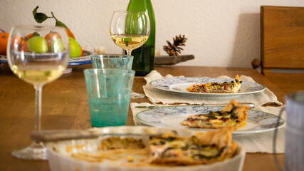 Festive lunch with homemade vegetarian quiche with zucchini, Swiss chard and cheese, white wine. Turquoise water glasses. 