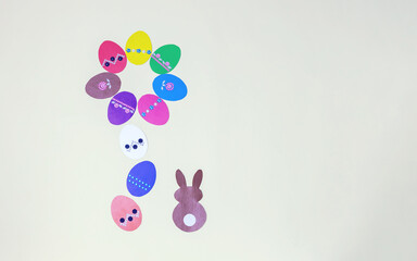 paper easter eggs laid out in the form of a flower and a rabbit on a light background