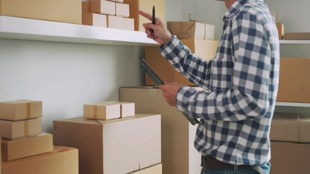 online business man receive order and is checking the quantity of products for delivered to the customer. Men write down amount of boxes for packing the product. Online business and home office.