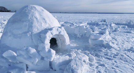 igloo and snow shelter in high snowdrift with mountains peaks on background - obrazy, fototapety, plakaty