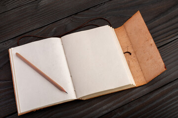 Open journal with pencil on a black table.