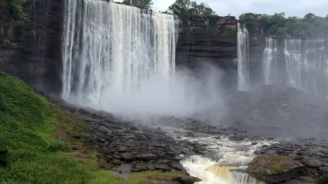 From the center of Calandula waterfalls in Angola rising up from the stream where the water hitting the black rocks and the mist all around the waterfall Aerial