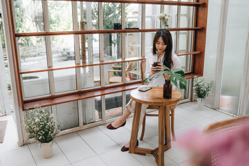 Fototapeta na wymiar Cute asian young woman sitting in cafe with coffee and phone