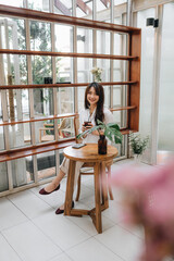 Cute asian young woman sitting in cafe with coffee and phone