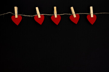 Red heart hanging on the clothesline, on black background. Valentines Day