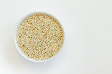 Sesame seeds in a glass bowl, isolated on white background. Top view.