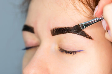 Young Caucasian Woman on the brow beauty procedures. Professional care for face. Brows coloring,...