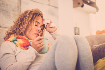 sick and unwell young woman feeling wrong with flu and some virus on the sofa at home. Female with...
