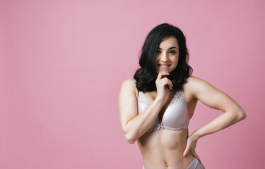 Image of a beautiful woman posing in lingerie on a pink colored background