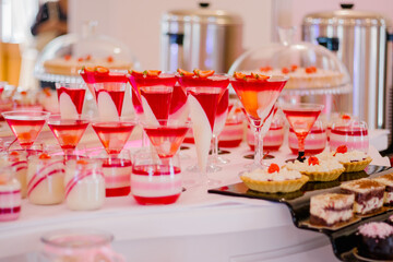 Wedding candy bar full of red and white desserts on a white table