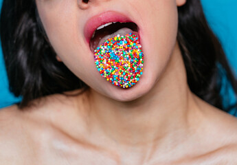 Artistic image of a female mouth with colored sprinkles on her tongue