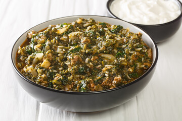 Delicious lunch beef stew with spinach, rice and onions close-up in a bowl on the table. horizontal