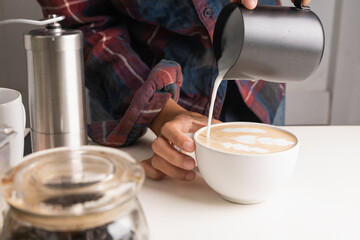 The professional of a barista poured milk. making latte coffee with equipment, tool brewing on bar at kitchen home