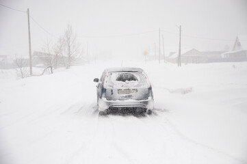 snowfall, a car on the road covered with snow