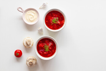 Homemade Traditional Ukrainian beet soup with fresh green dill. Russian borscht in bowl of tomatoes, sour cream mushrooms on white background