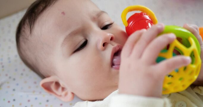 infant, childhood concept - close-up of smiling happy Baby plays with a teether. Teeth cutting. First teeth. Joy toothless 7 months baby bite, gnaws teether toy. slow motion