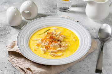 Chicken breast in a creamy broth. Chicken with vegetables and cream. Chicken soup in a bowl on the light gray kitchen table