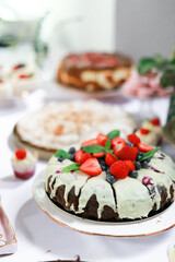 Chocolate dessert filled with icing and decorated with strawberries and mint on the table, candy bar