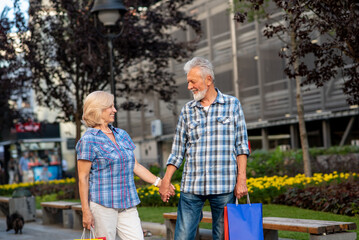 Happy senior couple with shopping bags looking at each other