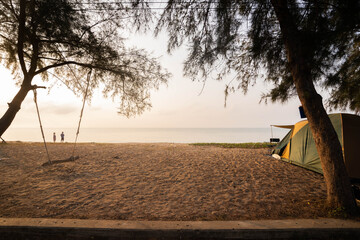In the morning tents and swings under the pine trees at the beach, couples stand happily at the beach on vacation.