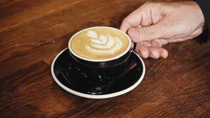 cropped view of man holding cup of cappuccino with latte art
