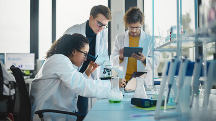 Medical Science Laboratory: Shot of Diverse Team Young Scientists Doing Analysis of Test Sample with Use of Microscope. Ambitious Young Biotechnology Specialists, working with Advanced Equipment