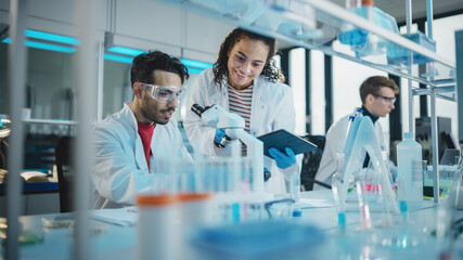 Modern Medical Research Laboratory: Portrait of Latin and Black Young Scientists Using Microscope,...