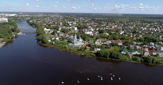 A drone shot of the wide and beautiful Volga river that flows through Tver, with many small sailboats swimming on it. People are enjoying the hot beautiful sunny summer day with a boating excursion.