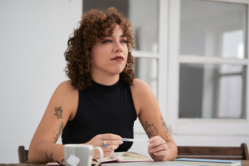 young entrepeneur girl with curly hair sitting at a table outside a terrace in Spain on a summer morning