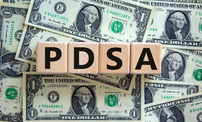 PDCA, plan do check act symbol. Wooden cubes with words 'PDCA, plan do check act'. Beautiful background from dollar bills, copy space. Business and PDCA, plan do check act concept.