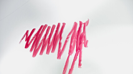 Obraz na płótnie Canvas top view of strokes of pink lipstick drawn on white