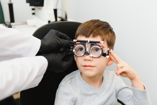 Cheerful child boy in glasses checks eye vision pediatric ophthalmologist.