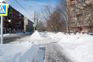 Fototapeta premium Winter city landscape. Large drifts along houses after a snowfall.